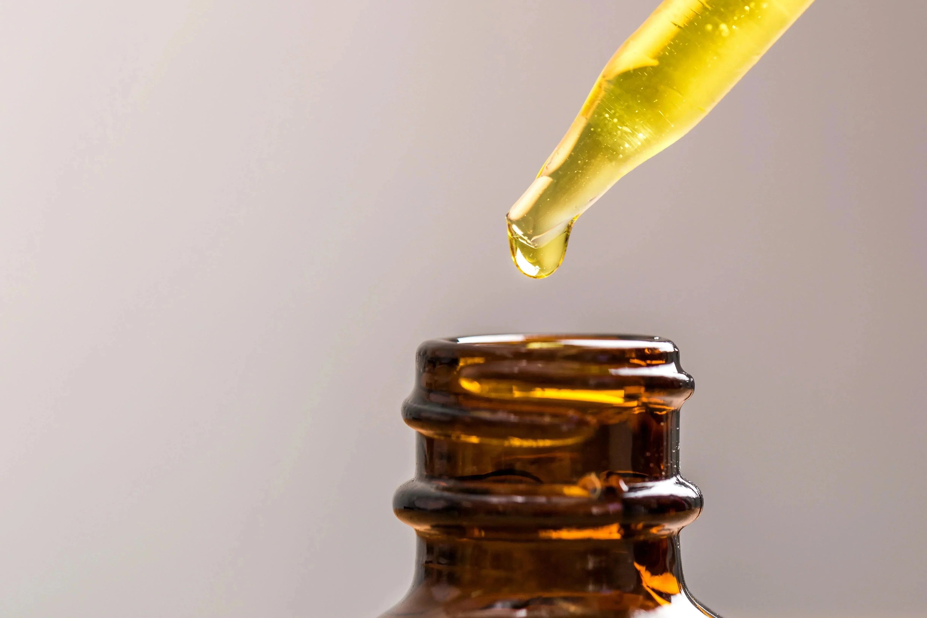 Dropper dispensing natural beard oil into amber bottle, Hairy Man Care grooming product