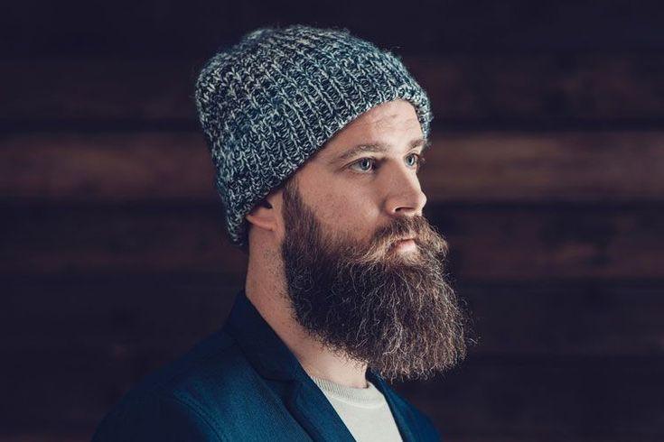 Man with full thick beard wearing knit beanie and jacket, beard grooming inspiration