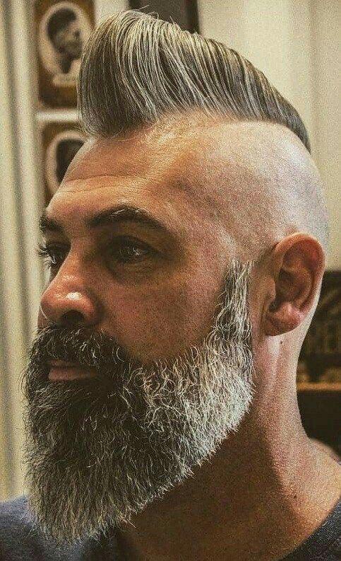 Man with a thick, groomed grey beard and styled undercut hairstyle in a barbershop