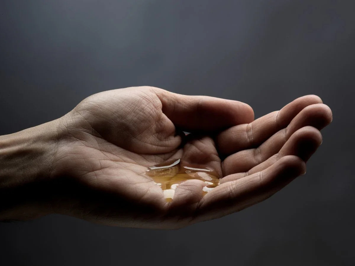 Hand holding natural beard oil, close-up on palm with grooming oil for softening beard