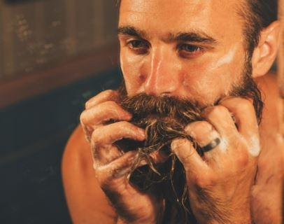 Man washing thick beard with shampoo, close-up of grooming and beard care routine