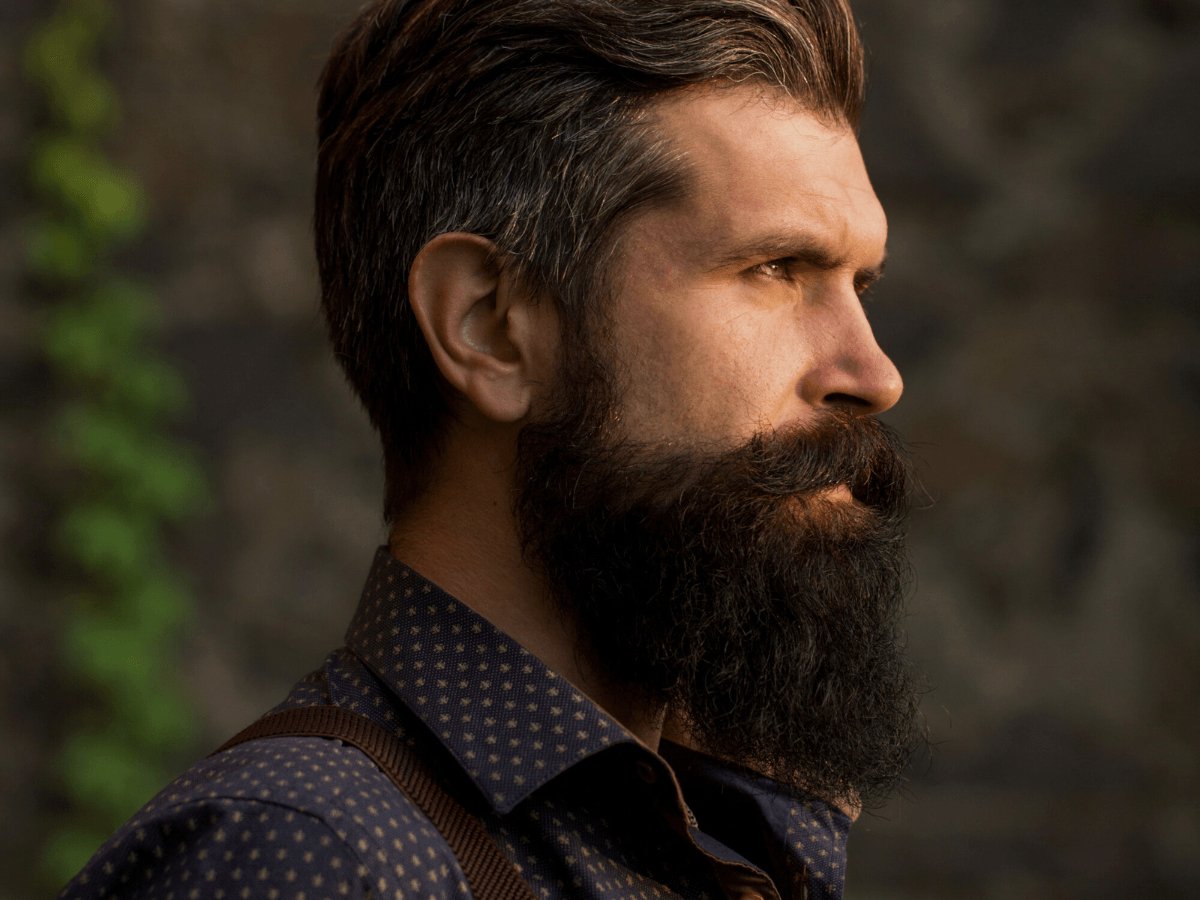 Side profile of a bearded man with well-groomed dark facial hair outdoors