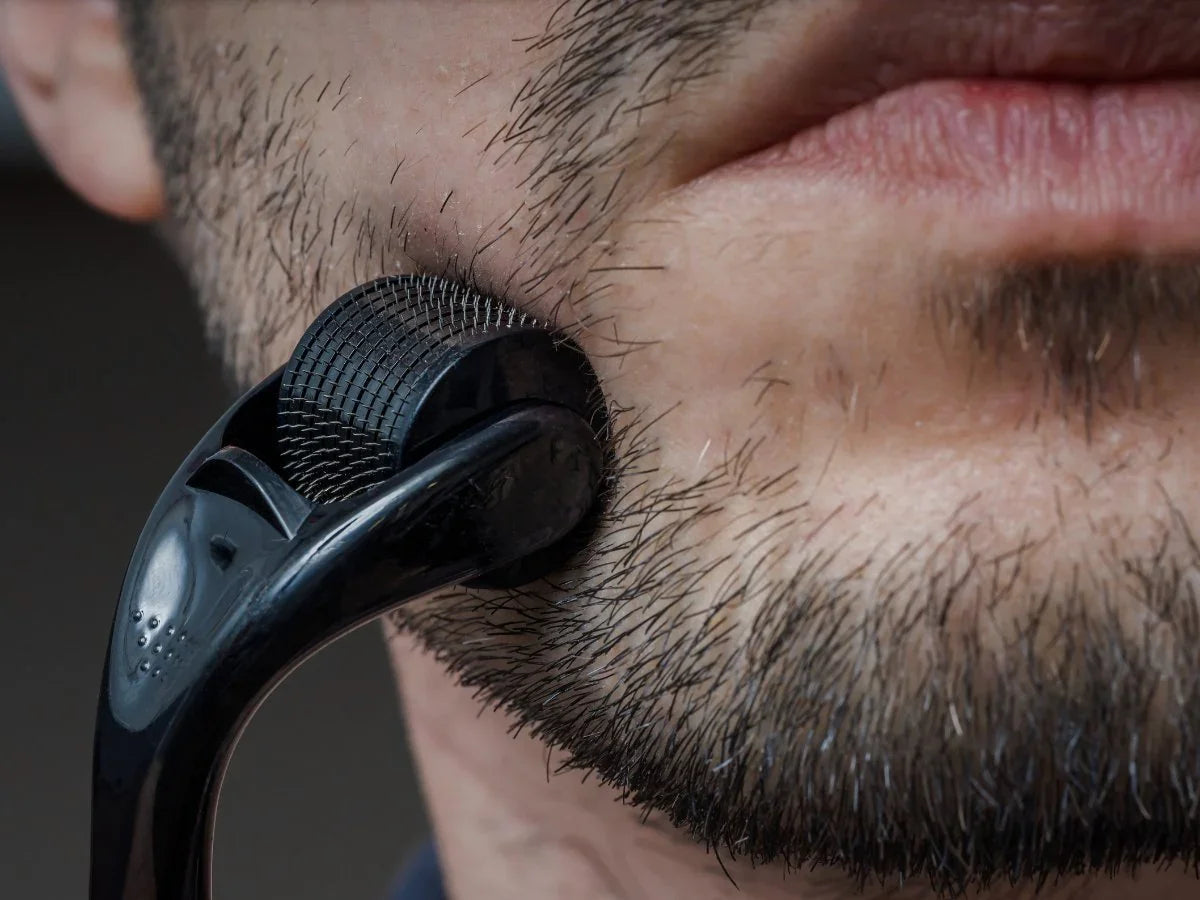 Close-up of man using a beard roller on stubble for beard growth
