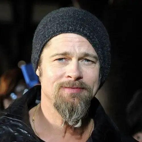 Man with a thick, styled goatee beard and knit beanie in a casual outdoor setting