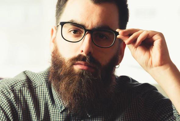Man with thick, well-groomed beard and glasses, close-up, natural beard care style
