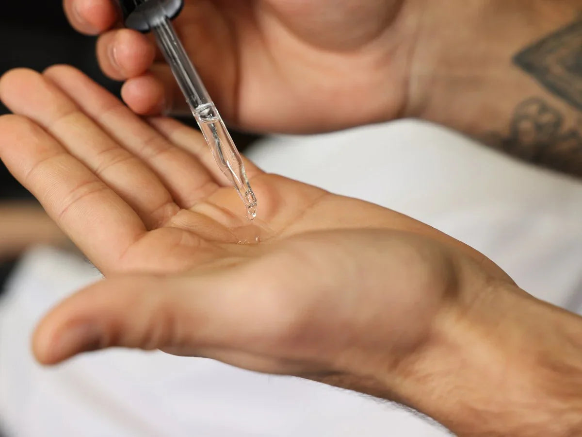 Hand applying beard oil with dropper for beard and skin care