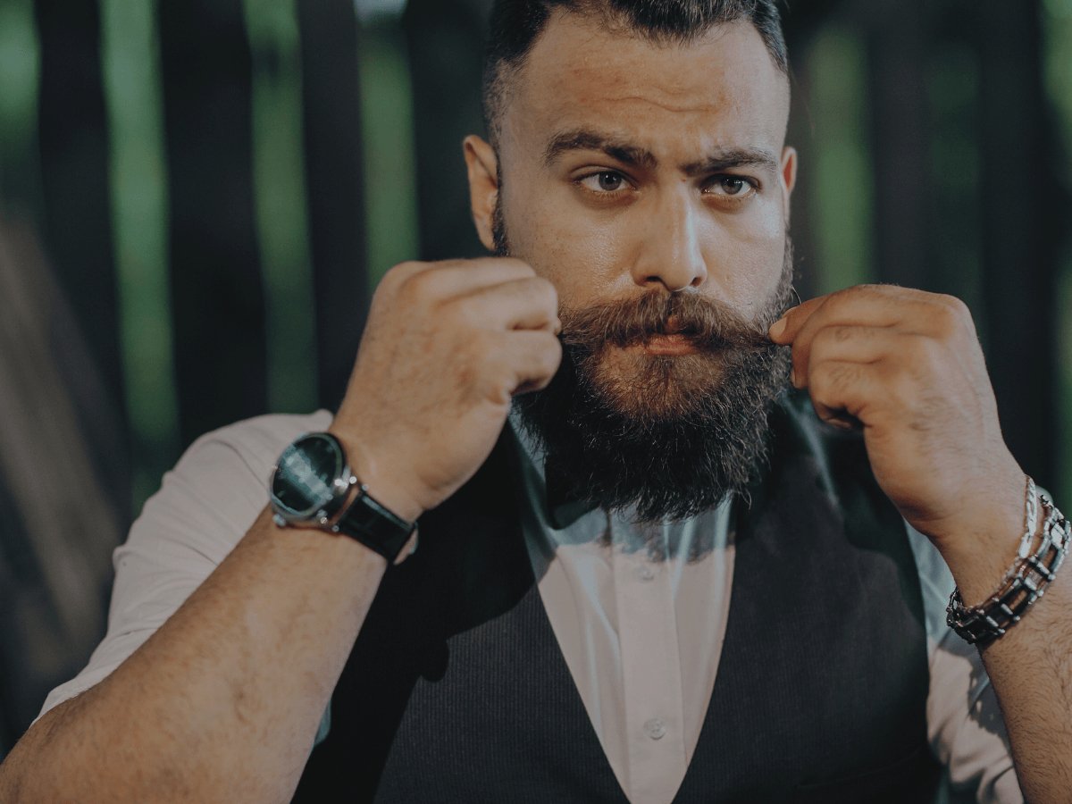 Man styling full beard and mustache, beard grooming and care outdoors