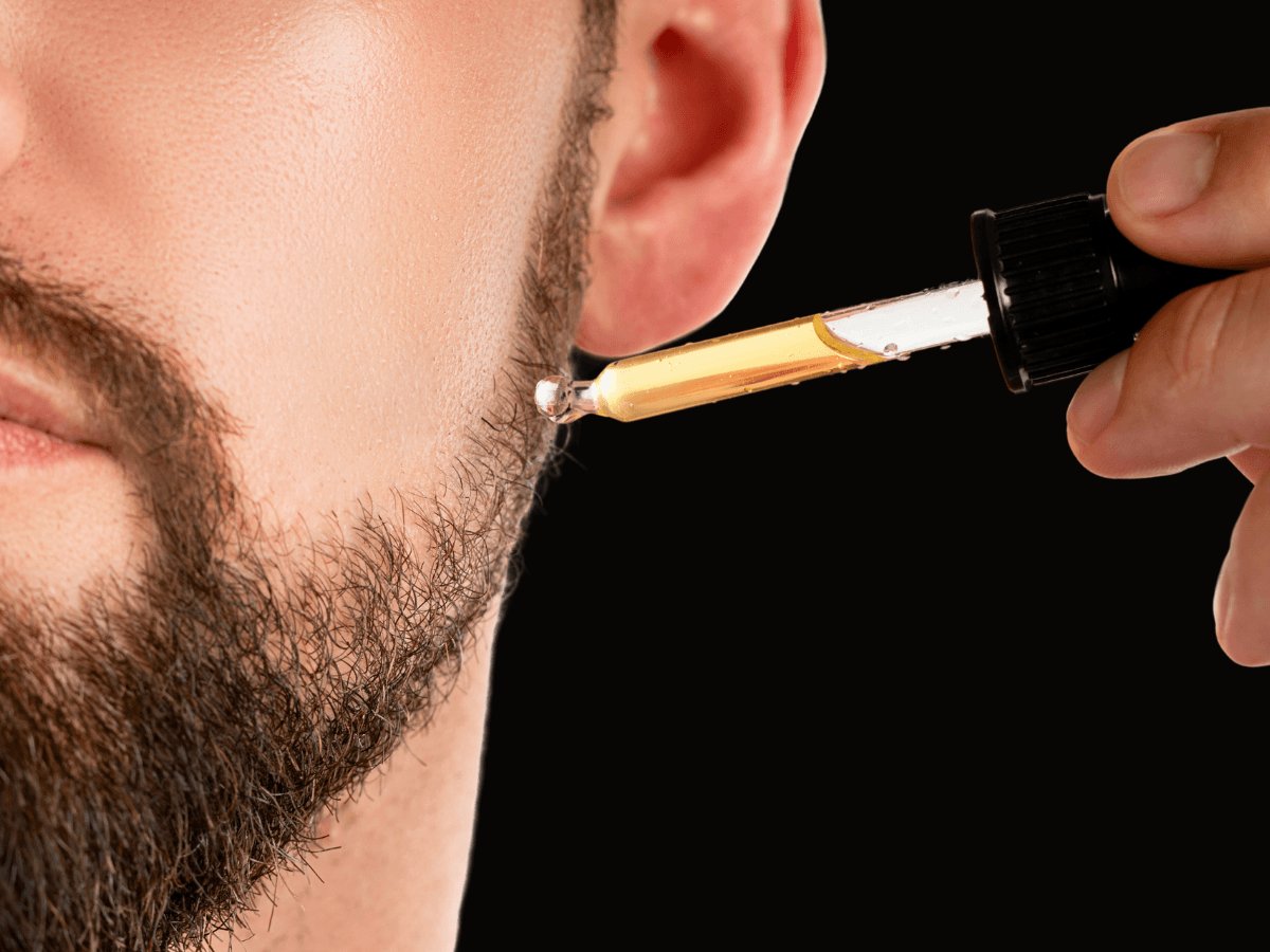 Close-up of man applying beard oil for beard growth and thickness with dropper