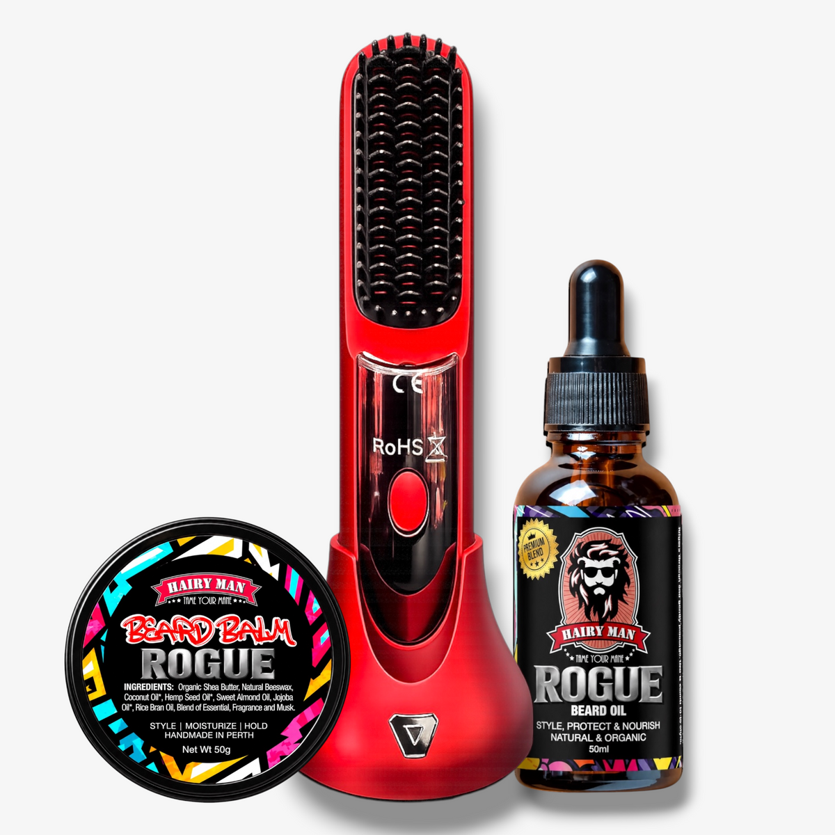 A grooming kit featuring a red electric beard straightening heat brush in its charging dock, a bottle of Hairy Man Rogue Beard Oil, and a tin of Hairy Man Rogue Beard Balm, arranged on a light gray background.